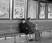 803879 Afbeelding van een wachtende man en vrouw op een bank op een perron van een onbekend station, met enkele ...